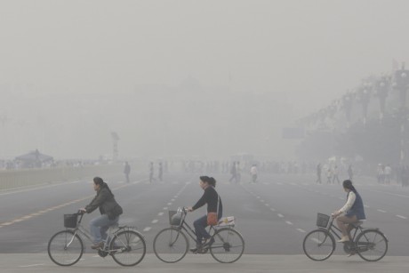 Chinese women cycle through smog and pollution over Beijing's Tiananmen Square