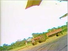 The tractor and trailer driven by the Twin Otter shooters, as recorded by Bob Brown of NBC News. One shooter is visible in front of the vehicle, having just fired a shot.