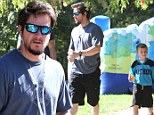 Safe and sound: Mark Wahlberg takes his son Michael to the park...while his brother Donnie's suffers Hurricane Sandy's aftermath