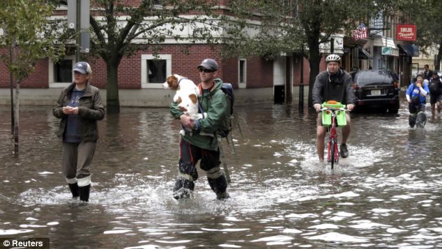 A man carries his dog as people make their way out of the flood waters in New Jersey