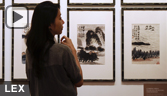 a woman inspects artwork by Chinese artist Qi Baishi entitled 'Landscapes'