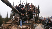 Free Syrian Army fighters pose on a tank, which they say was captured from the Syrian army