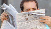 A man reads a copy of the Spanish newspaper El Pais