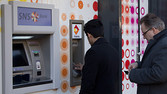 Two people use an ATM machine at an SNS bank in Amsterdam, Netherlands