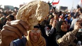 An Egyptian holds a piece of bread to protest against the high prices of goods in Tahrir square in Cairo February 8, 2013.