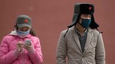 .A man and a woman wearing face masks stand by a wall inside the Forbidden City