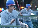 Batter up! Ashton Kutcher gets into the swing of things while teaching a female friend how to play baseball