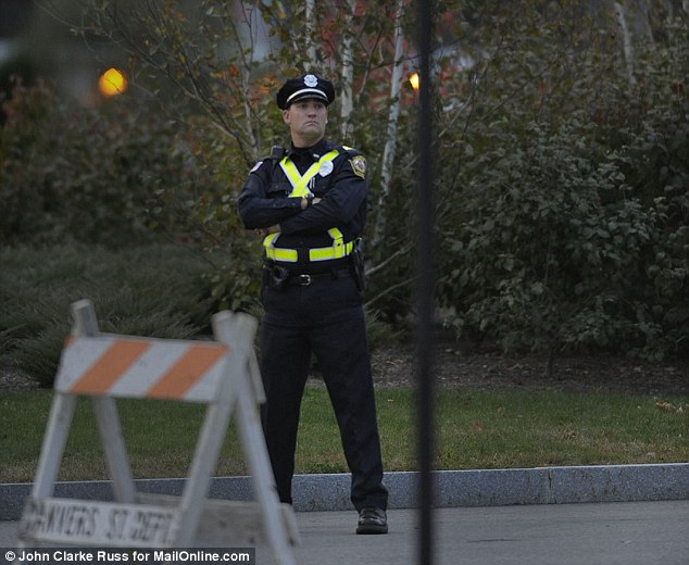 A police officer stands guard near the entrance to Danvers High School, Massachusetts on Tuesday evening 