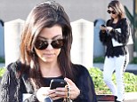 She's got her studs in order! Kourtney Kardashian takes care of business on her phone as she steps out in studded denim trousers and shaggy shirt
