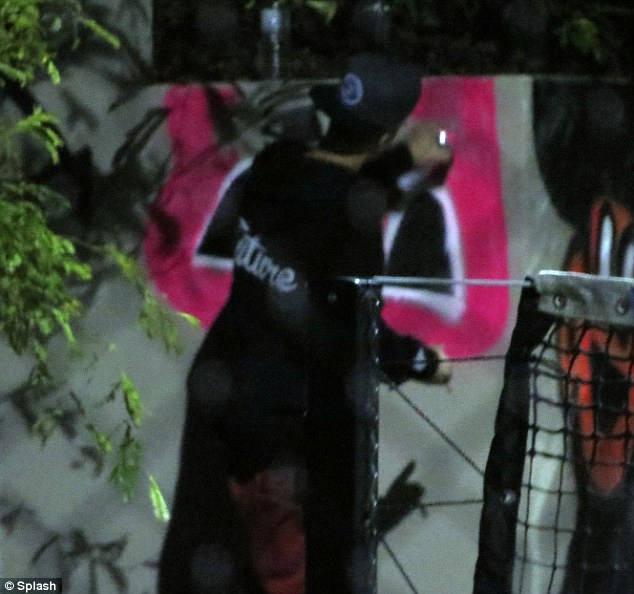 He's at it again: Justin Bieber was pictured doing graffiti on a wall near his hotel in Brisbane, Australia on Wednesday morning 