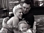 'Happy New Year!' Pink cuddles by the fire with husband Carey Hart and daughter Willow during snowy holiday in the mountains