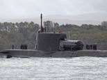The miniature submarine atop the HMS Astute, as manufacturers look on at its installation