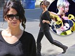Black-clad Selena Gomez looks tough in knee-high boots and 'feels sorry for' cardboard cut out-wielding rival Miley Cyrus