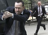 Action man! Donnie Wahlberg totes a prop gun as he shoots high-energy stunt scenes for his hit TV series Blue Bloods