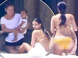 Kim Kardashian sunbathes in skimpy yellow bikini while her nanny holds baby North during Mexico getaway