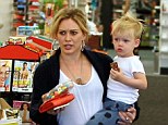 Juggling act: With her growing two-year-old balanced on one hip, the Disney star managed to carry both her bright red wallet and a big container of gummy worms in one hand as she headed to the check out