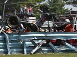 Wreckage from the race car of Michael McDowell (95) protrudes through the catch fence during a NASCAR Sprint Cup Series auto race at Watkins Glen International, Sunday, Aug. 10, 2014, in Watkins Glen N.Y. The crash and resulting damage to the protective barriers resulted in race stoppage for over an hour. (AP Photo/Derik Hamilton)