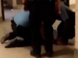 This still from a cellphone video shows two school police officers holding down a young woman while another stands over her