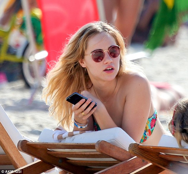 Is that Bradley on the phone? While she kicked back on a sun lounger Suki played on her phone 