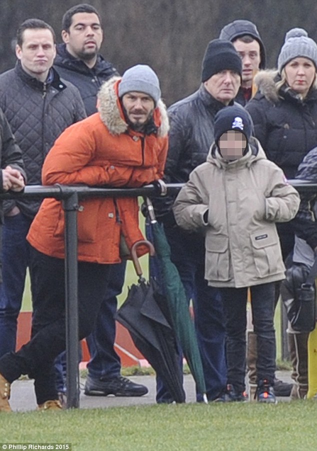 Standing out from the crowd: It was hard to miss hunky Beckham in his bright orange parka 