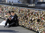 FILE - This Wednesday April 16, 2014 file photo shows a newly wed couple resting on the Pont des Arts in Paris, France. Any hope that the love locks that cling to Paris¿ famed Pont des Arts bridge would last forever _ will be unromantically dashed by the city council who plan to dismantle them Monday _ for good. (AP Photo/Remy de la Mauviniere, File)