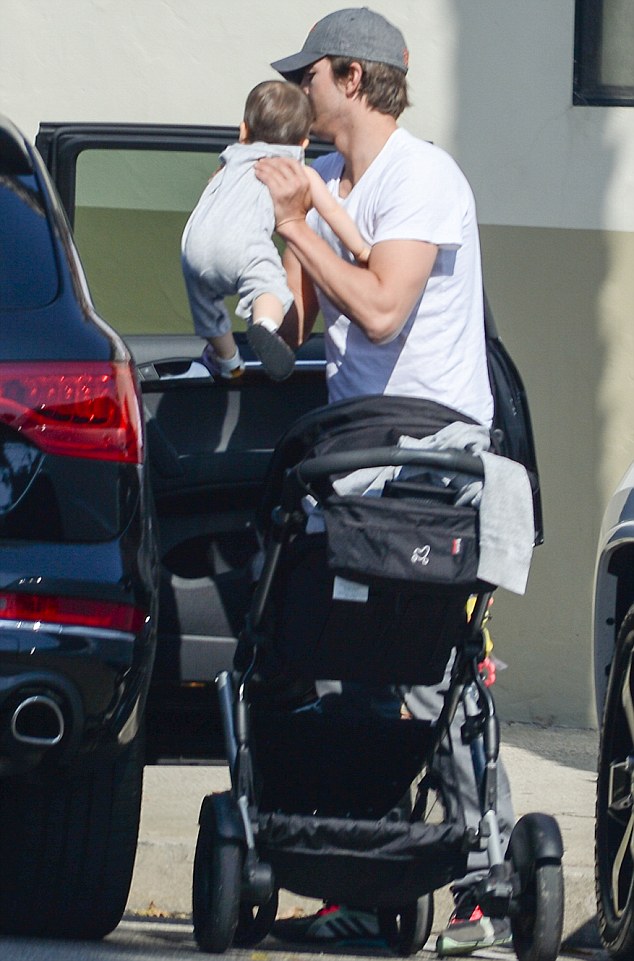 His favourite role: Ashton was spotted lifting the eight-month-old from her stroller and into the car