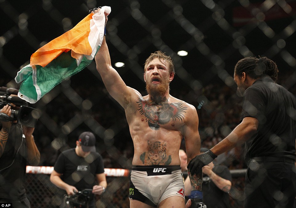 Conor McGregor celebrates with the Irish flag after stopping Chad Mendes in the second round to win the UFC interim featherweight title