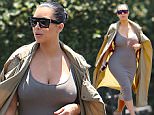 Thursday, July 16, 2015 - Kim Kardashian squeezes her growing baby bump into a tight, ribbed dress and covers up with a long trench during an outing to Fred Segal in West Hollywood.  The pregnant reality star had a secret fan learing at her from a storage unit in the parking lot.  Creepy! \nAdriano/X17online.com