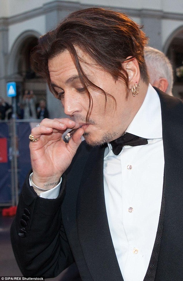 Getting his fix: Johnny Depp, 52, displayed his love for the finer things in life on Saturday, taking a puff from a cigar as he attended The Danish Girl red carpet alongside his glamorous wife Amber Heard, 29 
