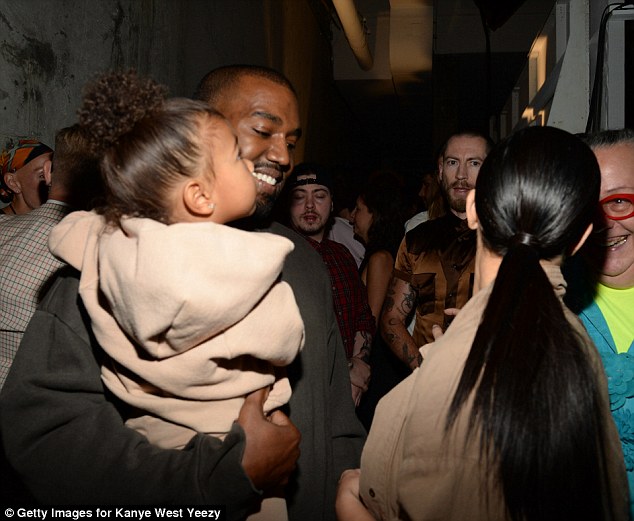 Proud father: Kanye looked happy to carry his bundle of joy as wife Kim stood nearby