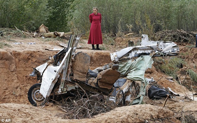 A woman looks at a damaged vehicle swept away during a flash flood in Hildale, Utah