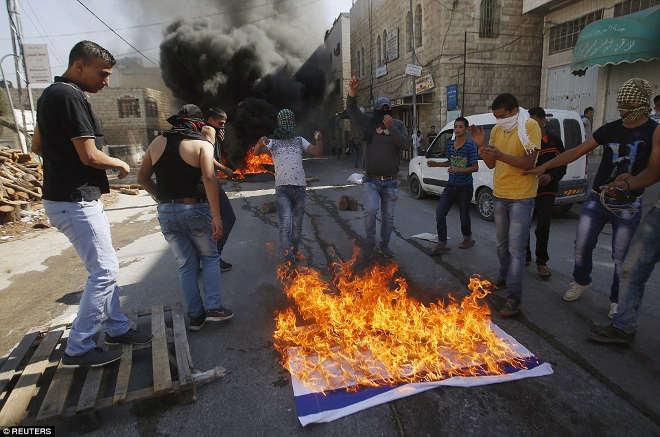 Unrest: Hebron has been a scene of violence for days. Palestinian youths are pictured above last Friday burning an Israeli flag
