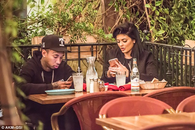 If you can't beat 'em: Tyga could be seen joining in on the fun and checking his phone, as Kylie continued to play on her iPhone