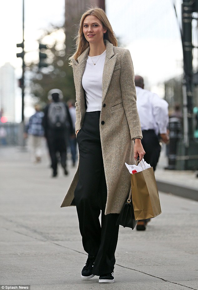 Cool and casual: Karlie, 23, nailed transseasonal styling in her comfortable ensemble which comprised black high-waisted trousers, cropped white jersey top, nude blazer coat and adidas trainers