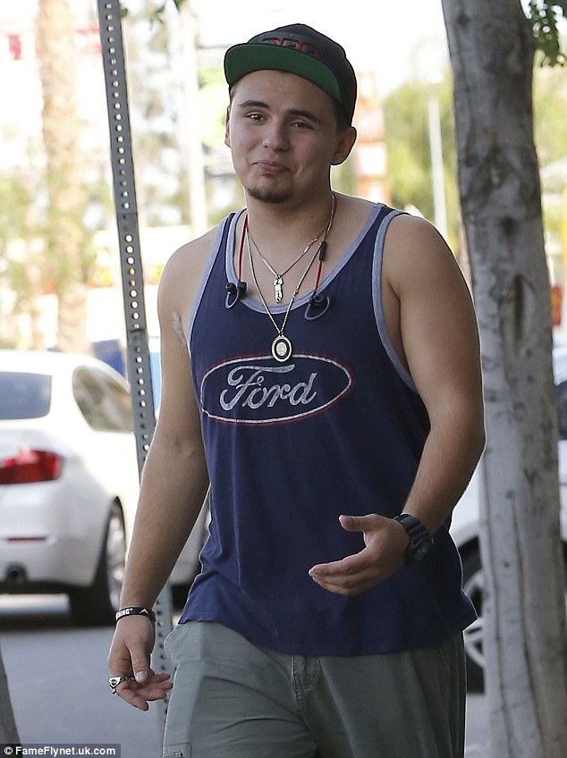 Relaxed: Choosing to keep cool in the warm climes, he flashed some muscle in navy tank top, emblazoned with the Ford logo 