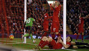 Liverpool players look dejected around the goalmouth as scorer Mane wheels away to celebrate his late equaliser at Anfield