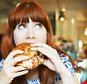 A woman eating hamburger in a cafe.
