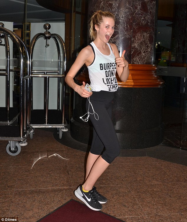 Natural beauty: Wearing a pair of fitted black tights and a white tank emblazoned with 'Burpees Don't Like You Either,' the 5' 10'' model appeared flushed as she posed for photographs in the lobby of her hotel