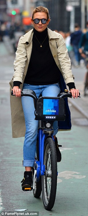 Beautiful even on a bike: For her excursion, the former Victoria's Secret Angel kept things chic yet practical, opting for a thick black turtleneck under a long, billowing tan trench coat with red accents and a striking midnight blue lining