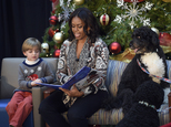 First lady Michelle Obama, sitting with Stephen Orzechowski, 5, left, and Bo Obama, right, reads "Twas the Night Before Christmas" to a group of children at the Children¿s National Health System in Washington, Monday, Dec. 14, 2015. Her appearance continued a first lady tradition that dates back more than 60 years to Bess Truman, who first brought holiday cheer to children not well enough to leave the hospital in time for Christmas. (AP Photo/Susan Walsh)