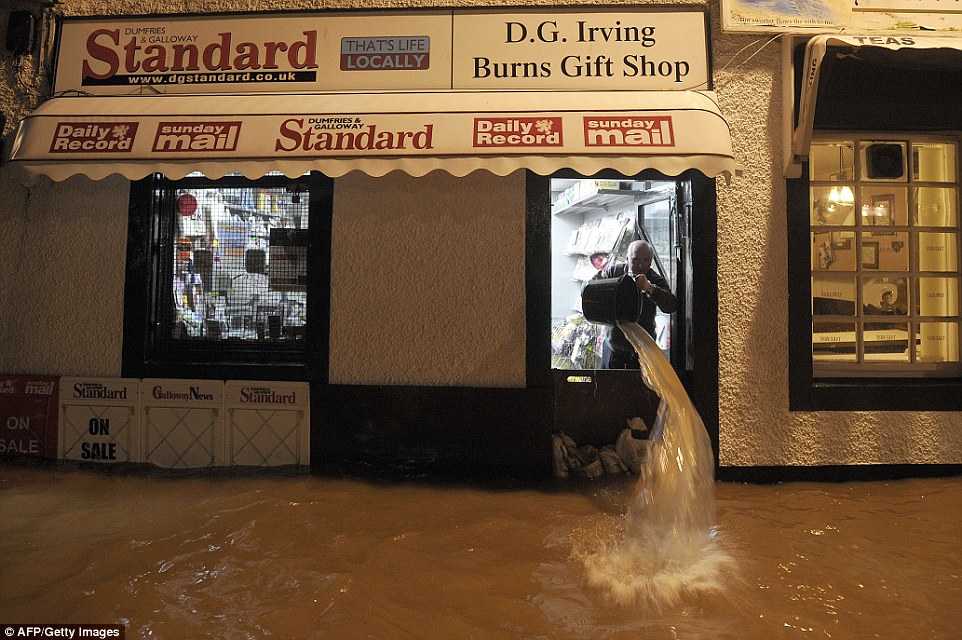 Trying his best: Shopkeeper Donald Irving bails floodwater out if his shop after the River Nith burst its banks in Dumfries