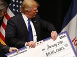 Republican presidential candidate Donald Trump distributes a check to Puppy Jake during a campaign event at the Adler Theater, Saturday, Jan. 30, 2016 in Davenport, Iowa. (AP Photo/Paul Sancya)