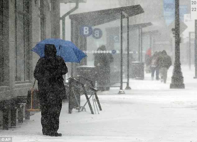 A passenger waits in the snow to board a bus at Kennedy Plaza in Providence, Rhode Island on Monday