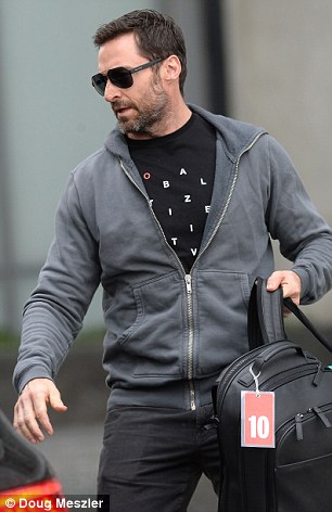 Sun damage: Hugh wore a black top underneath his grey hooded jacket and completed the ensemble with black jeans and aviator shades