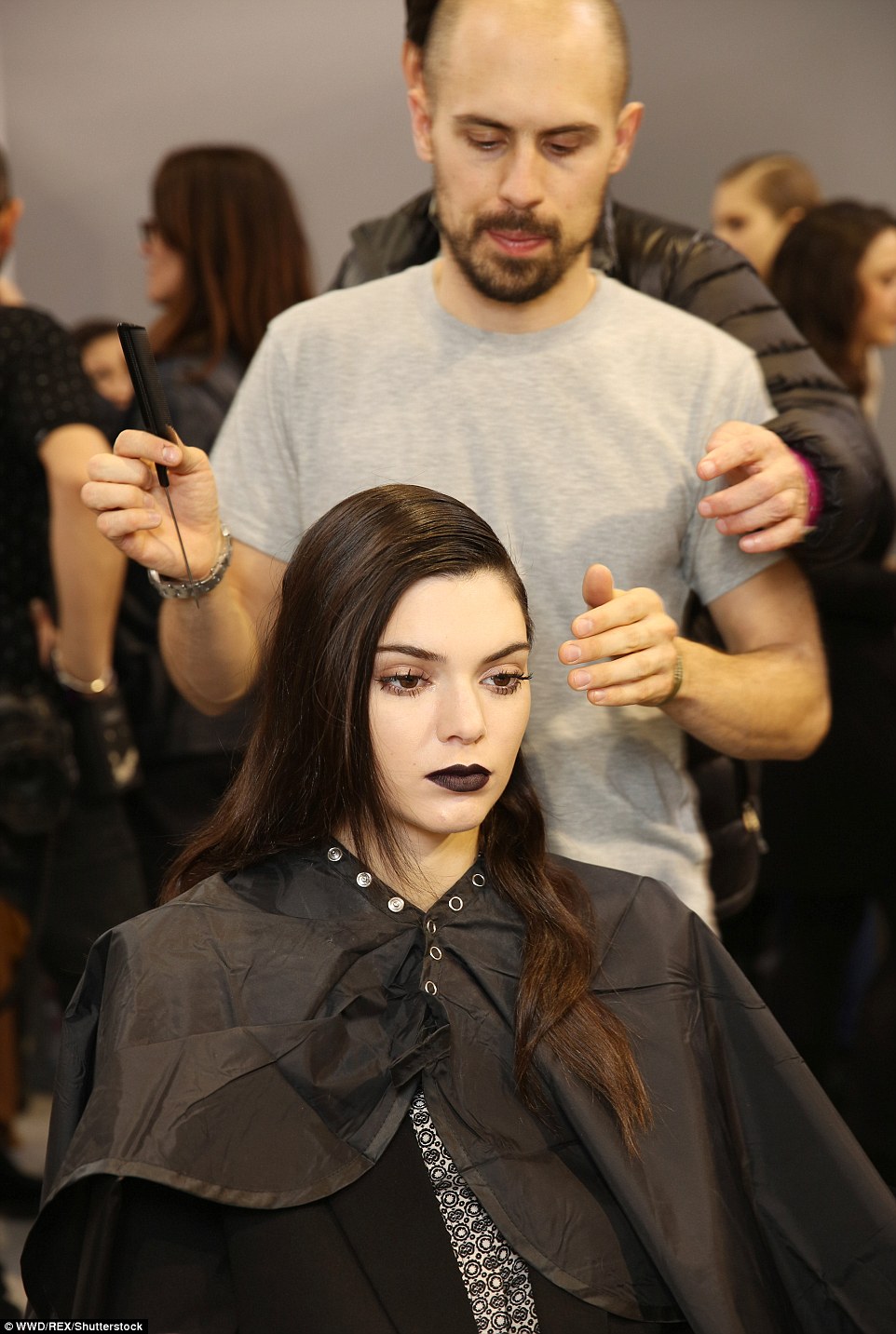 Finishing touches: Kendall was pictured in hair and makeup backstage, with her black lips looking dramatic against her pale skin, while a stylist got to work slicking back her locks