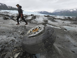 FILE - In this June 10, 2015 file photo, U.S. Marines Capt. David Gooch, with the Defense POW/MIA Accounting Agency, walks past an aircraft wheel assembly resting on the ice surface of Colony Glacier in Alaska. The Air Force says it's identified more remains of service members who died when a military transport plane slammed into the Alaska mountain six decades ago, killing all 52 people aboard. Military officials say 31 victims have been recovered and identified since the wreckage of the C-124 Globemaster was rediscovered four years ago. An Alaska Army National Guard helicopter crew flying over the area spotted the debris about 50 miles northeast of Anchorage. (Bill Roth/Alaska Dispatch News via AP, File)KTUU-TV OUT; KTVA-TV OUT; THE MAT-SU VALLEY FRONTIERSMAN OUT; MANDATORY CREDIT