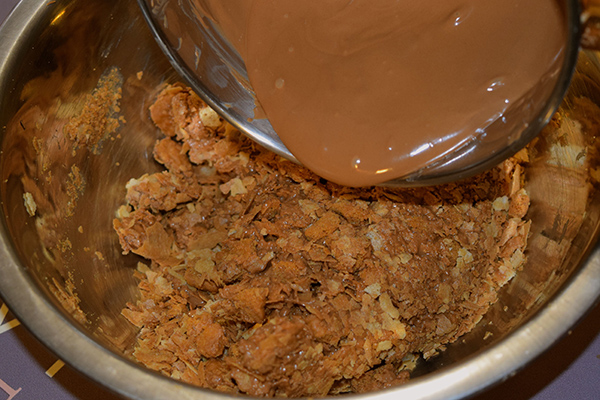  Once chocolate is totally melted, pour it immediately into the bowl with crushed biscuits. Stir strongly before   it cools down.