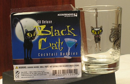 Picture of box of black cat cocktail buddies and a glass with a cat hanging from the rim