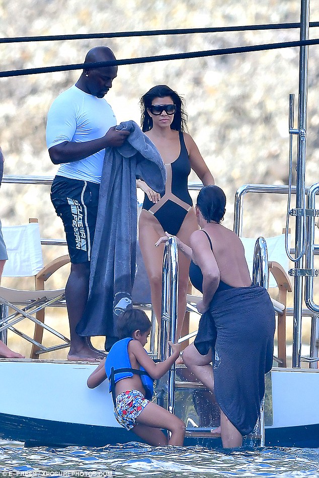 Such a gent: Corey held out a towel as his lady love emerged from the sea with a towel already wrapped around her waist while Kourtney looked on