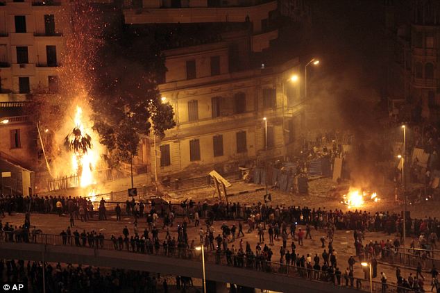 A city ablaze: Pro-government demonstrators, bottom, clash with anti-government demonstrators, top right, as a palm tree burns from a firebomb, in Tahrir Square
